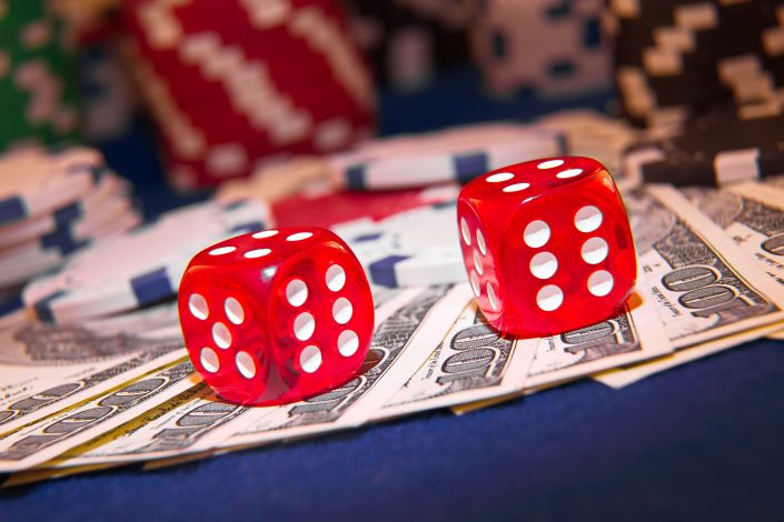 Stack of Poker chips with dice rolls on a dollar bills,