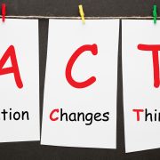 Action Changes Things (ACT) written on set stickers with clip hanging on a rope on black background.